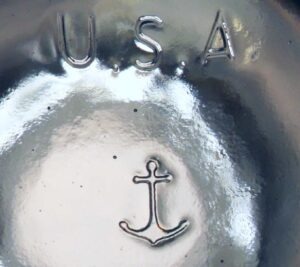 Anchor mark on base of clear glass milk bottle, made circa 2019 or 2020.