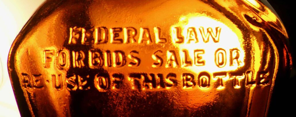 Federal Law Forbids Sale or Reuse of this bottle - phrase on amber liquor bottle made by Owens-Illinois, Glass Company, marked D-23 / 65-57 on the base.