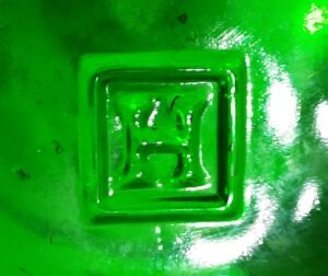 "H in a square" trademark as it appears on the base of an emerald green beer or soda bottle made by Hemingray Glass Company, Muncie, Indiana in the 1924-1935 period. 