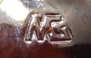 MG-connected mark as embossed on the bottom of a liquor or wine bottle made by Maywood Glass Company of Compton, California.