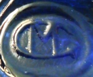 M inside a G logo on base of blue glass bottle made by Maryland Glass Corporation