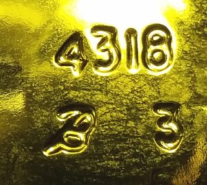 "Cursive B" mark used by Ball Glass Container Corporation during the 1994-1995 period. Shown as it appears on the base of a light yellow ("dead leaf green") wine bottle.