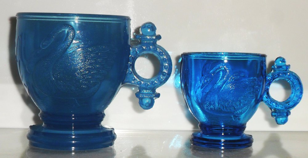 Two blue "Swan with Ring Handle" children's mugs, attributed to Atterbury & Company, circa 1880s.