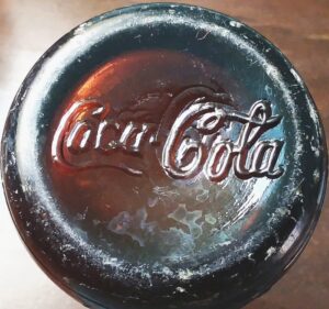 Coca Cola in script lettering on base of amber Lexington Ky soda bottle made by D.O.C. (Dominic O. Cunningham), circa 1910