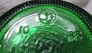 "FF inside a circle" trademark used by Foster-Forbes Glass Company, here on base of emerald green soda bottle made in 1986.