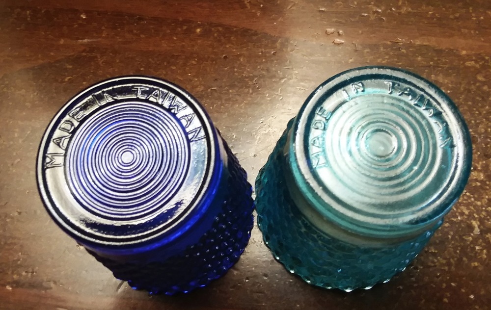 Bases of two "MADE IN TAIWAN" colored glass votive candle holders.