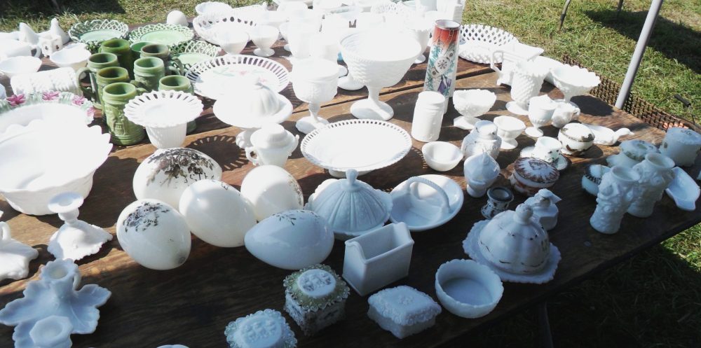 Assortment of vintage and antique white Milk Glass at an outdoor flea market including large Victorian-era blown glass eggs. 