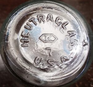 Neutraglas embossed mark on base of small clear glass vial made by Kimble Glass Company.