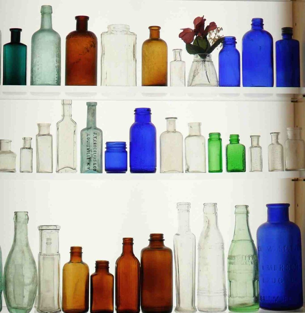 Small collection of Old Antique Bottles of various colors and types, lined up on shelves.