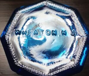 "WHEATON NJ" on base of sapphire blue decorative, octagonal ink bottle marked "CARTER". Made by Wheaton Glass Company, Millville, New Jersey.