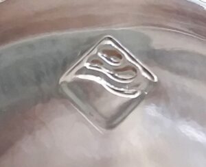 Square - diamond mark with waves design on base of clear glass bottle