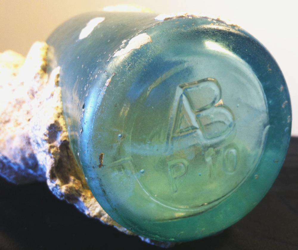 AB / P 10 bottle (encrusted with coral) as found off coast of Maui. (Photo courtesy of Betsy Sears).