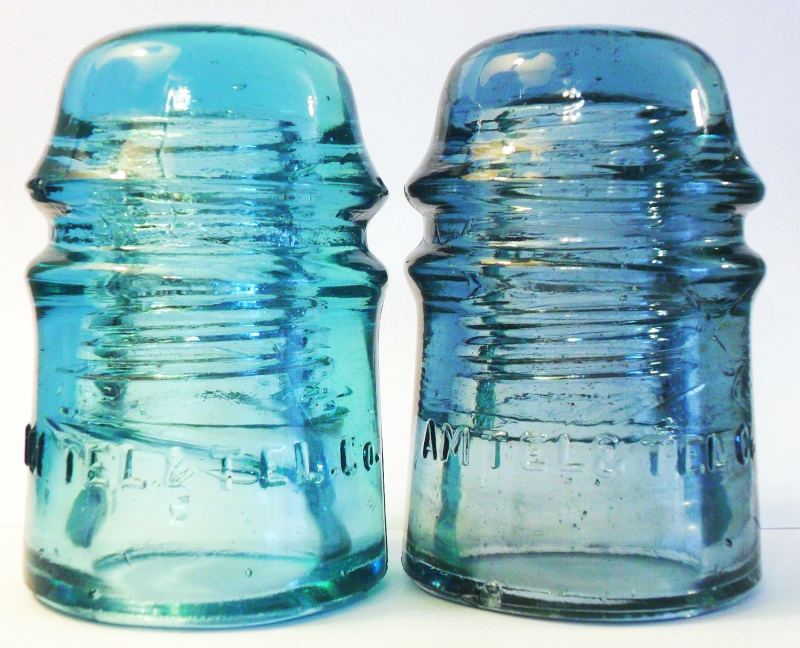 Two "AM TEL & TEL CO" toll insulators made by Brookfield Glass Company for AT&T CO in the 1900s-1910s. The piece on left is the natural as-found aqua color. The example on RIGHT has been irradiated which has produced an odd "cornflower" or "dingy sapphire" blue shade. 