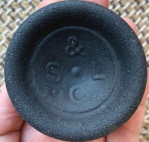 "S & L C" or "C S & L" mark on base of blackglass bottle. This is a partial base shard of "beach glass". (Photo courtesy of Peg M.)