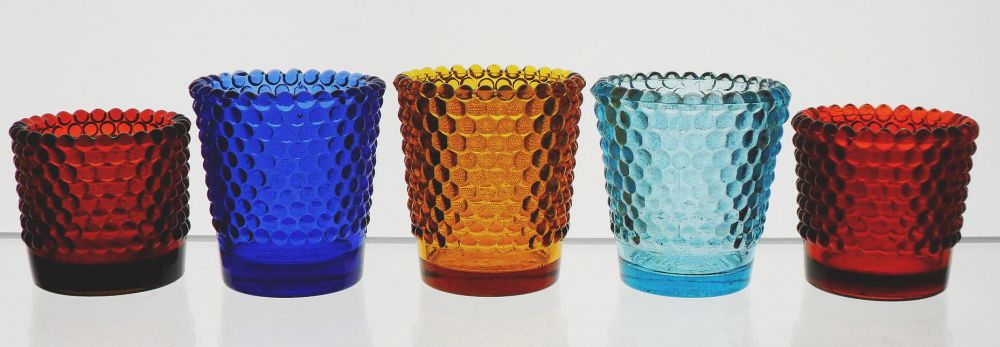 Hobnail Votive Candle Cups (from left to right): Red or Reddish Amberina, marked "PAT JULY 11, 1939"; Cobalt Blue, marked "MADE IN TAIWAN"; Amber, marked "MADE IN U.S.A./10"; Aquamarine, marked "MADE IN TAIWAN"; Ruby red, smooth base with no markings.