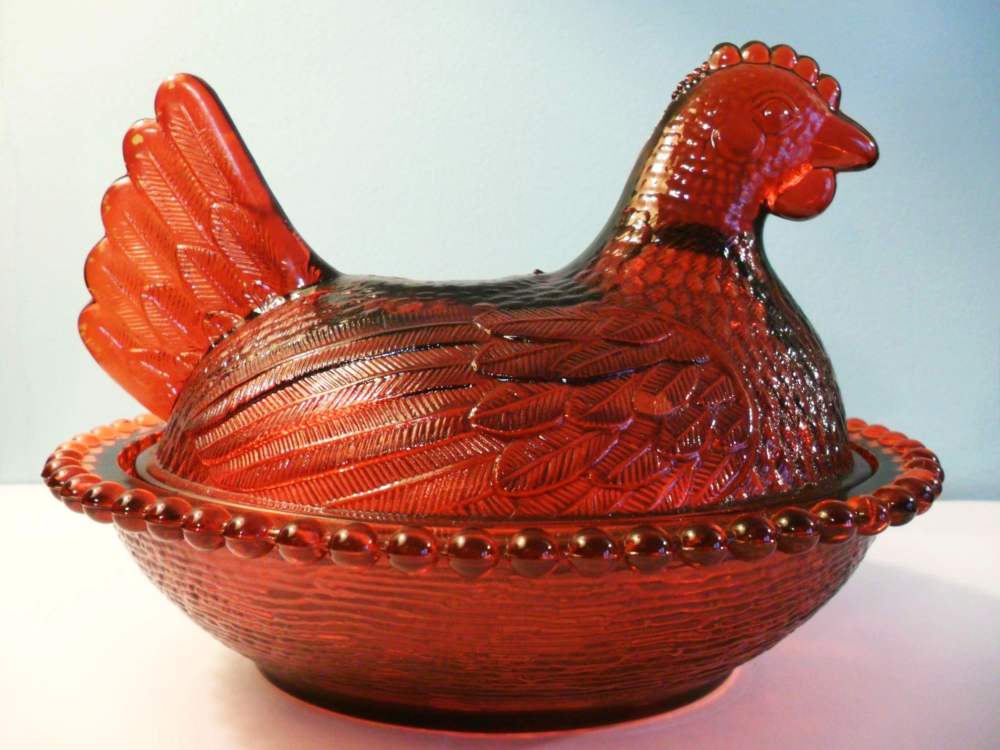 "Ruby Red" hen made by Indiana Glass. The color does not extend throughout the glass, but is actually a thin red coating (stain) over a light amber glass.