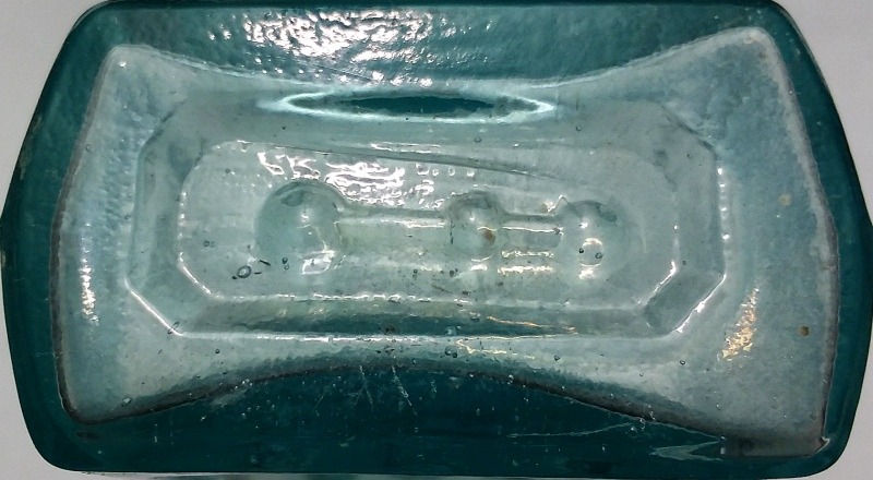 Base of a typical rectangular aqua Whittemore bottle, one of the earlier versions with an indented frame on front for label. This one marked with three "bumps" on base. The dots probably served as a mold identifier.