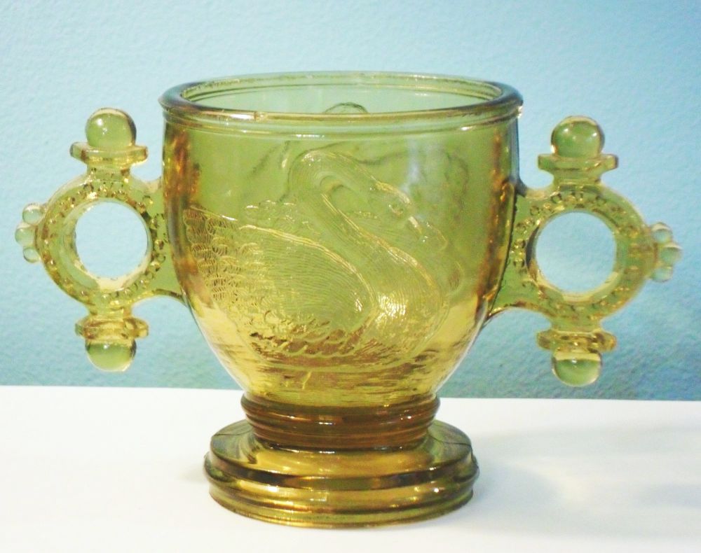 Atterbury & Company -- Swan with Double-Ring Handles Mustard or Sugar Bowl in amber colored glass. This is usually seen in white milk or opaque. 