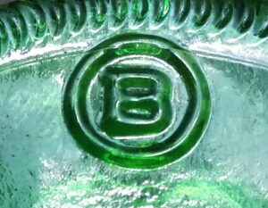 "B in a circle" trademark used by Brockway Glass Company, on base of emerald green soda bottle with 1985 date code.