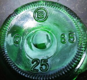 Base of emerald green soda bottle made by Brockway Glass Company in 1985. This bottle bears an "O" where the plant location code usually appears.  This "Zero" has not been explained (so far), and appears on many soda bottle molds. Is it possible it stands for their Oakland, California plant?