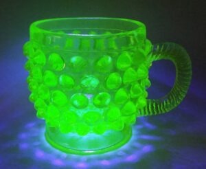 Canary / Vaseline glass EAPG mug, hobnail pattern dating from the 1880s or 1890s. This is the same mug (as shown above) under UV light.