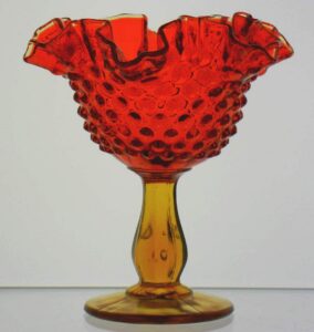 Hobnail pattern open compote / candy dish with ruffled rim, in Colonial Orange (Amberina) glass. Their "Cursive Fenton inside an oval" mark is on the base.