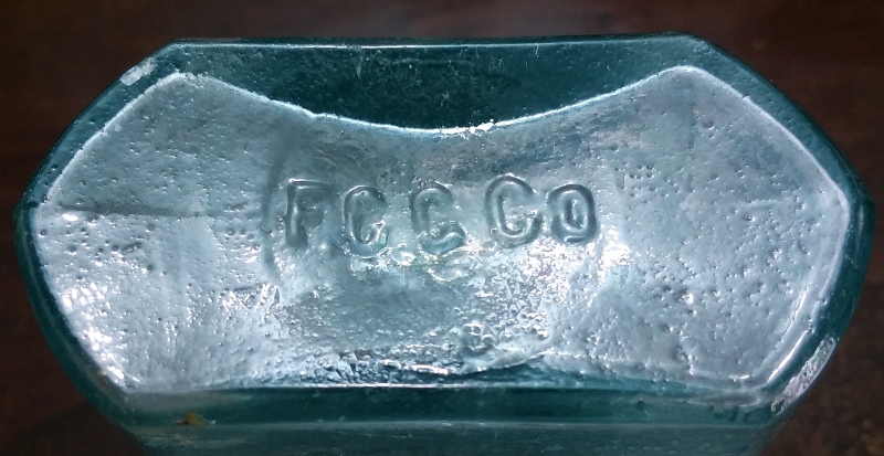 F.C.G.Co. mark on the base of an aqua half-pint "Coffin" or "Shoofly" style liquor flask. 