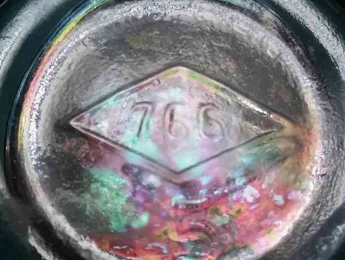 "766" inside a diamond - mark on the base of a small "generic" light aqua bottle made by Illinois Glass Company. This identified the bottle as the "No 766" mold in catalogs and invoices. (This bottle has some very light iridescence from long burial, similar to the look of "Carnival Glass")