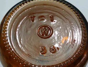 "W inside a circle" mark - Wheaton Glass Company - on base of small amber serum or vaccine bottle.