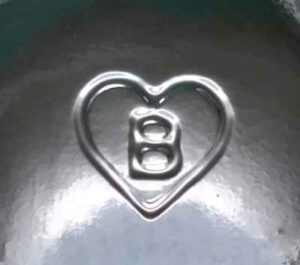 "B inside a heart" trademark used by Berlin Packaging, based in Chicago, Illinois. The mark is seen here on the base of a clear packer jar.