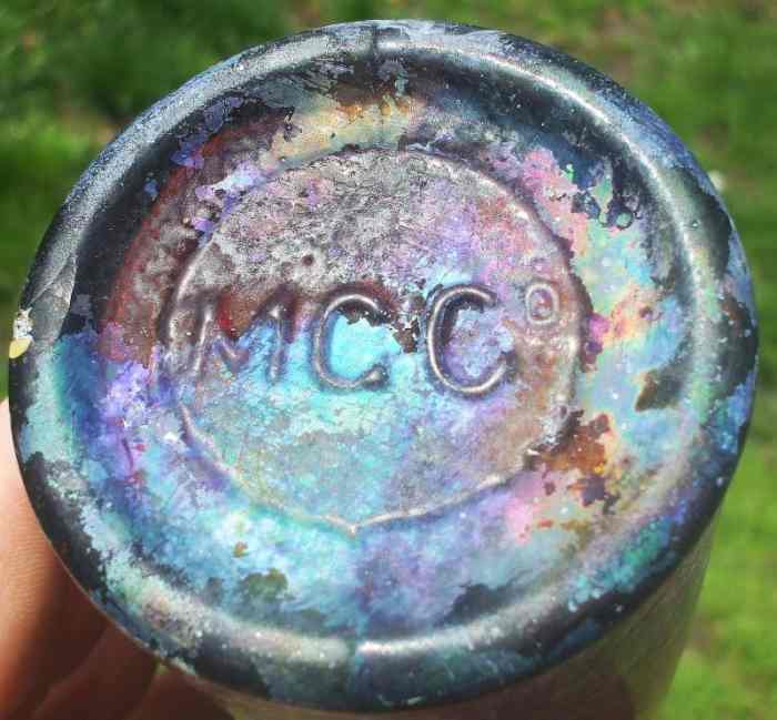 M.G.Co. mark on base of export style beer bottle, product of Mississippi Glass Company. The bottle shows heavy rainbow iridescence "patina" on glass surface. (Photo courtesy of Vanessa Fleming, ebay seller "thenessabrook")