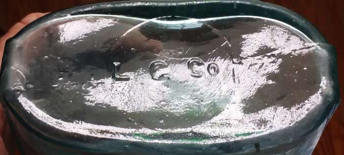 "L G Co" mark on base of quart-size aqua strap sided flask - circa 1870s-1880s. This is probably a product of Lindell Glass Company, but solid proof is lacking! "L G Co" mark on base of quart-size aqua strap sided flask - circa 1870s-1880s. This is probably a product of Lindell Glass Company, but solid proof is lacking!