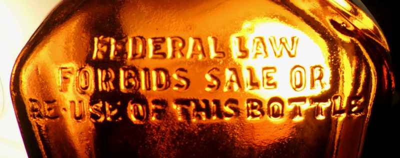 Federal Law Forbids Sale or Reuse of this bottle - phrase on amber liquor bottle made by Owens-Illinois, marked D-23 / 65-57 on the base.