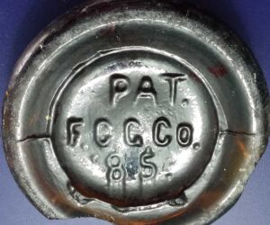 "PAT. F. C. G. Co. '85." mark on base shard from amber beer bottle made by Falls City Glass Company. (The 1885 date alluded to the so-called "Baltimore Loop" seal or closure patented by William Painter and used by many bottlers for a number of years). 
