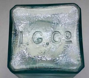 "I. G. Co." mark on base of mouthblown aqua square "cabin" or "schoolhouse" ink bottle made by Illinois Glass Company. "I. G. Co." mark on base of mouthblown aqua square "cabin" or "schoolhouse" ink bottle made by Illinois Glass Company.