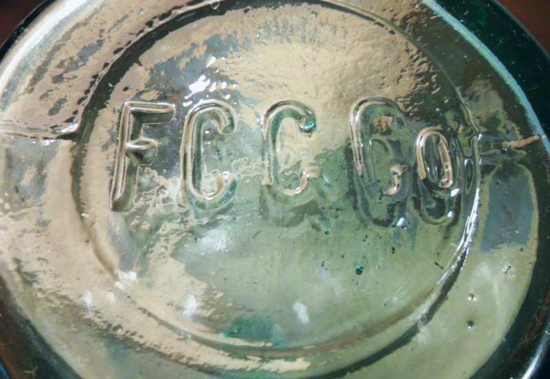"F.C.G.CO." on base of aqua chemical/packer bottle made by Falls City Glass Company of Louisville, Kentucky.