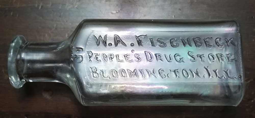 "W. A. FISCHBECK / PEOPLE'S DRUG STORE / BLOOMINGTON, ILL" - colorless one-ounce druggist bottle. This bears an "M inside a diamond" on the base (standing for John M. Maris, a pharmaceutical products distributor).   This probably dates from the 1890s-1910s era.