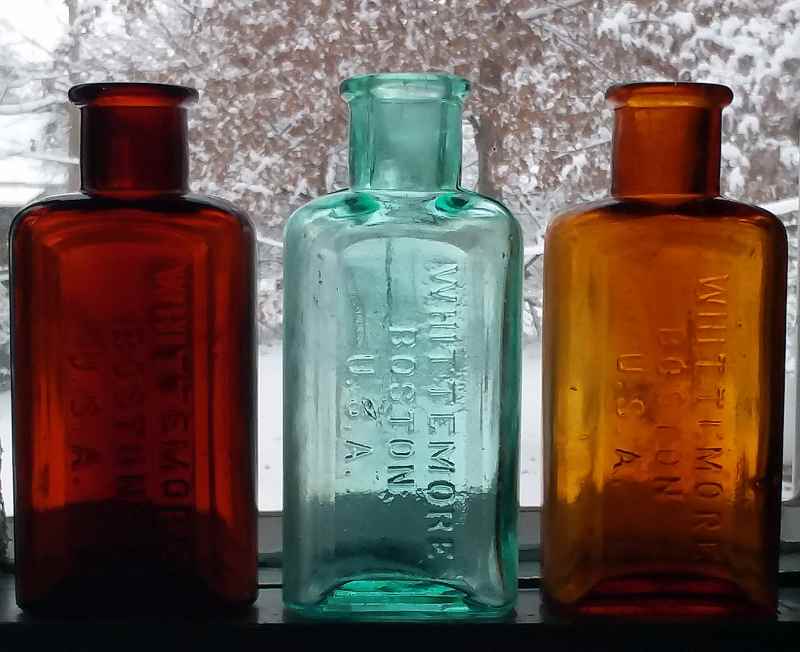 Three WHITTEMORE BOSTON U.S.A. bottles - dark amber, medium aqua, lighter shade of amber.  The color is quite accurate with a snowy background! 