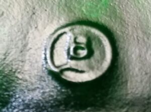 B with wavy underline inside circle, glassmaker mark used by Glashutte-Budenheim GmBH, Germany, as seen on green Jagermeister bottle