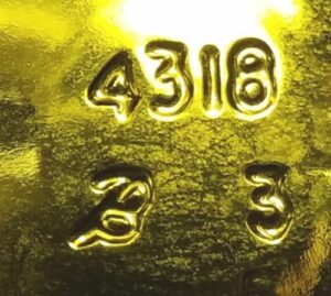 "Cursive B" mark used by Ball Corporation during the 1994-1995 period. Shown as it appears on the base of a light yellow ("dead leaf green") wine bottle.