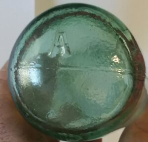 "A" on rounded base of light green "Torpedo" mineral water bottle made in Great Britain - likely (but not confirmed with absolute certainty) a mark used by Alloa Glass Work, Scotland. 