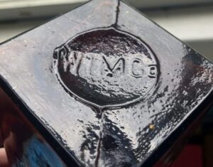 "W I M Co" on base of West India Stomach Bitters bottle (photo courtesy of Miles Burke) W I M Co - West India Manufacturing Company made this bottle - West India Stomach Bitters bottle - photograph of the mark on base - photo courtesy of Miles Burke.