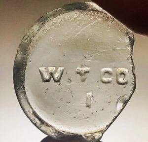 W.T.CO. (Whitall Tatum Company) mark on bottle base shard (Photo courtesy of Jodi Gerstenhaber). W.T.CO. (Whitall Tatum Company) mark on bottle base shard (Photo courtesy of Jodi Gerstenhaber).