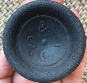 "S & L C" or "C S & L" mark on the base of black glass bottle. This is a partial base shard of "beach glass". (Photo courtesy of Peggy M.) 